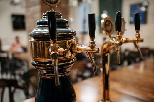 Detailed view of classic beer taps at a bar, showcasing polished metal and wood textures.